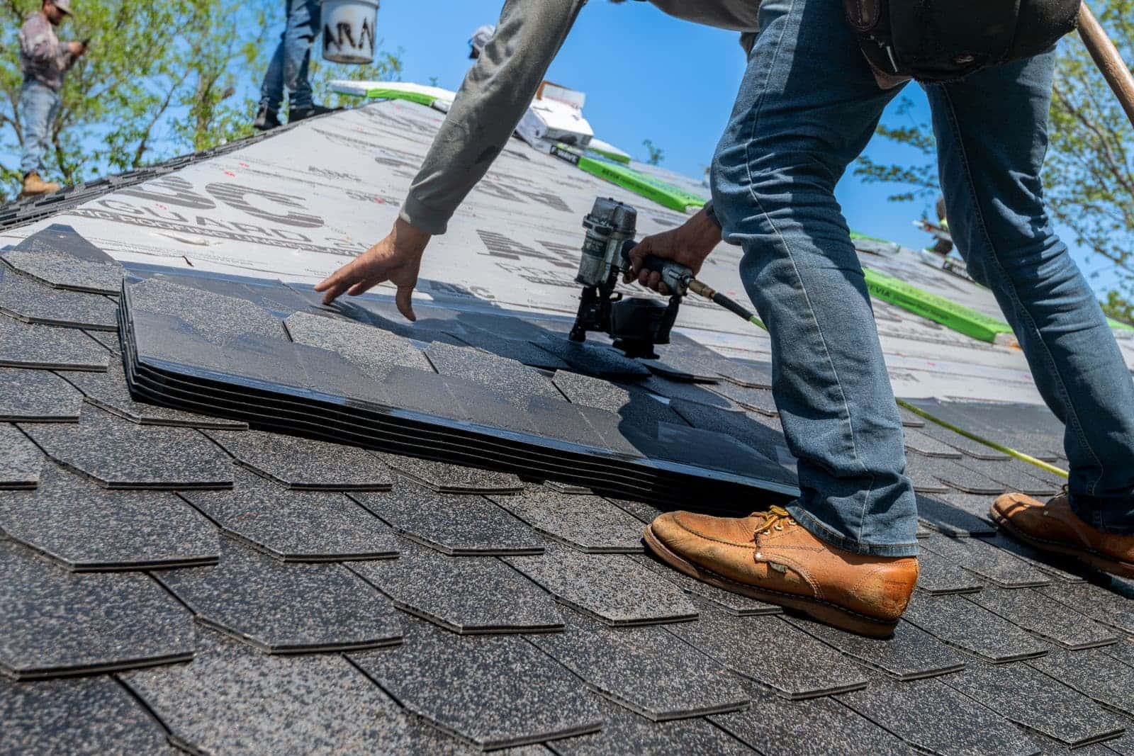 Roofer nailing architectural shingles during a roof repair